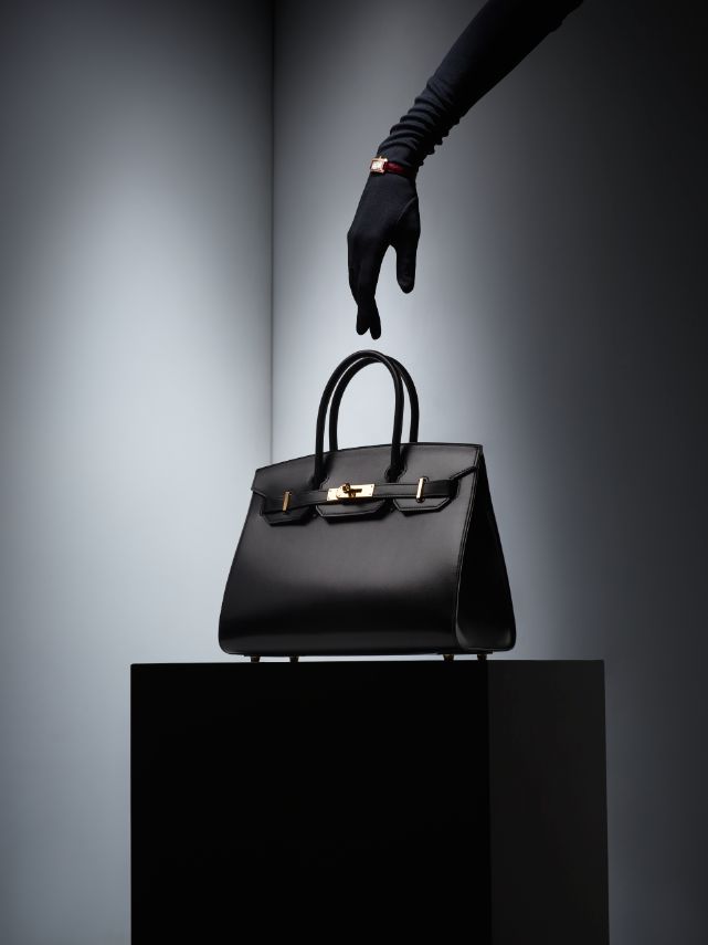A gloved hand reaching for a handbag
